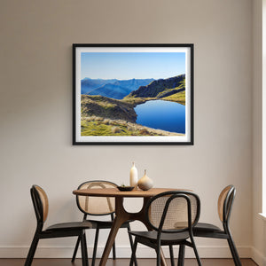 Framed landscape print of a mountain tarn on the St Arnaud Range above a dining table with chairs.