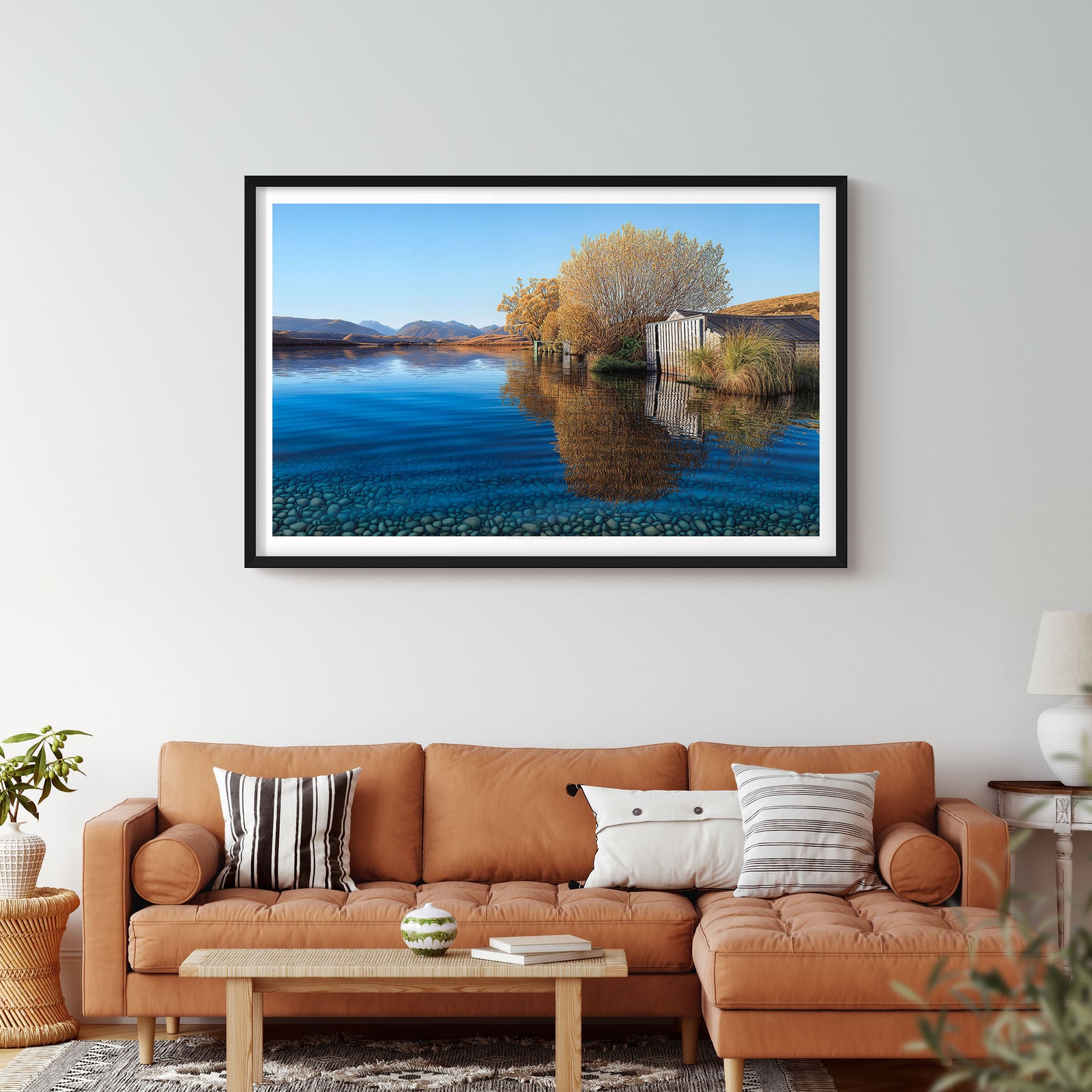 An artwork depicting a serene lake scene with a boat shed, tree, and clear blue water reflecting the sky at Lake Alexandrina.