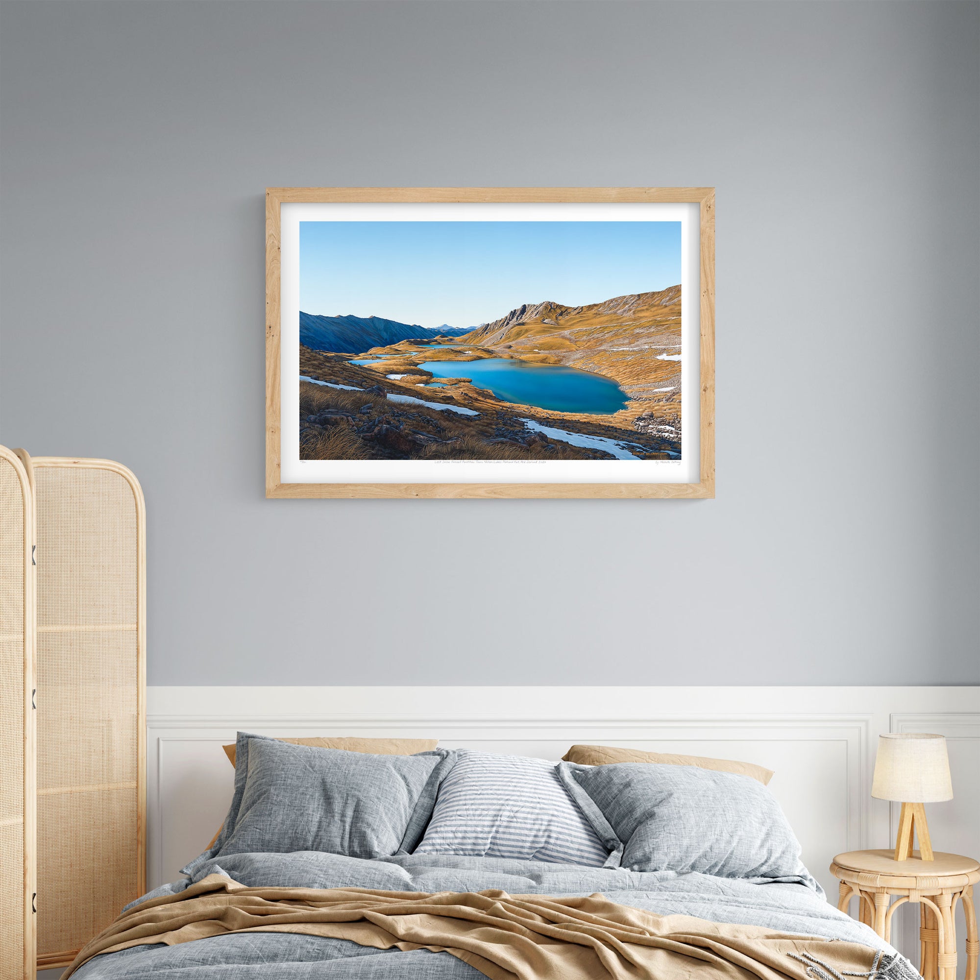 A framed art print above a bed of the Paratitahi Tarns in the by local artist Michelle Bellamy.