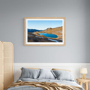 A framed art print above a bed of the Paratitahi Tarns in the by local artist Michelle Bellamy.